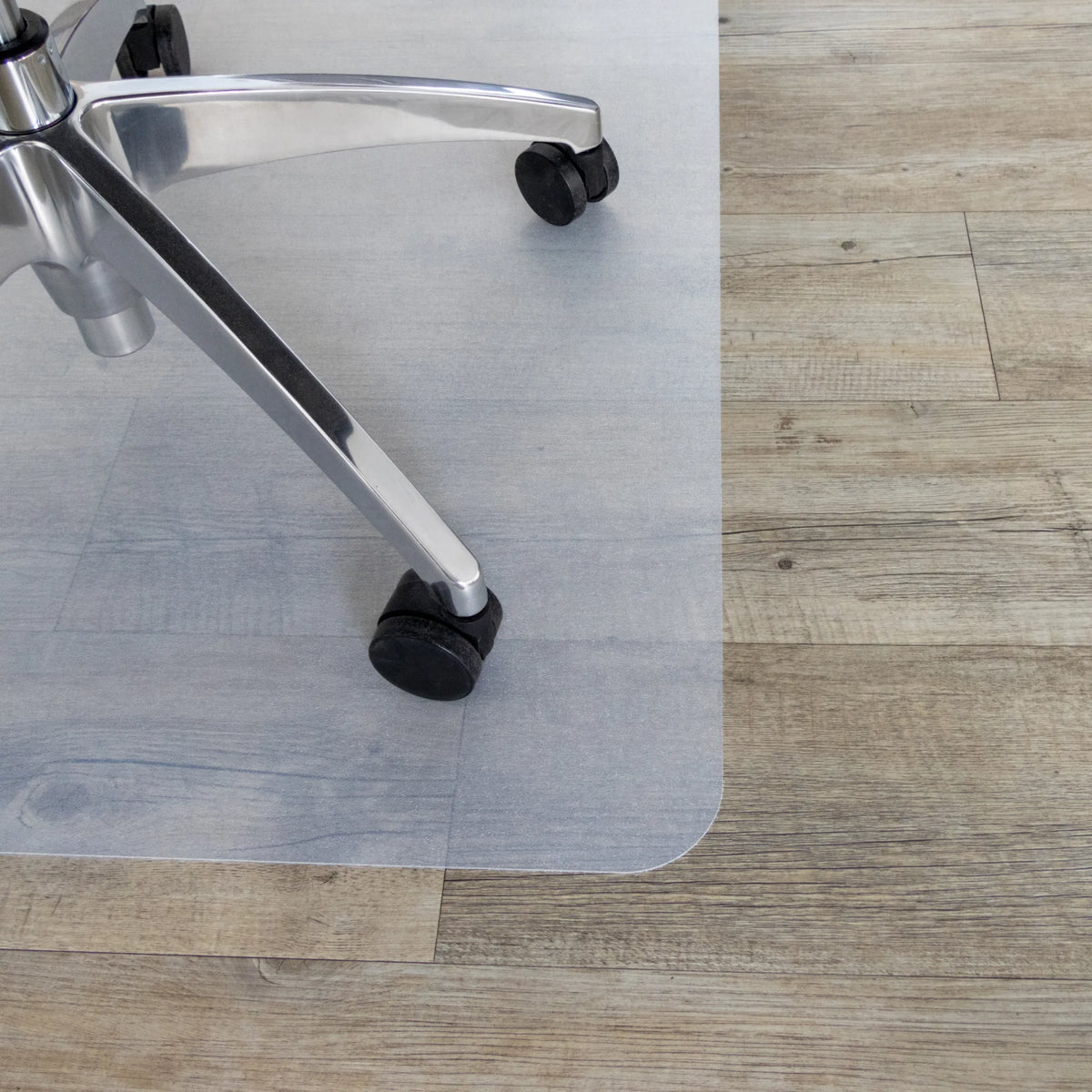 Ruedas de una silla de oficina sobre la alfombrilla FORTIFLEX de color blanco lechoso en un suelo de madera de hjh OFFICE