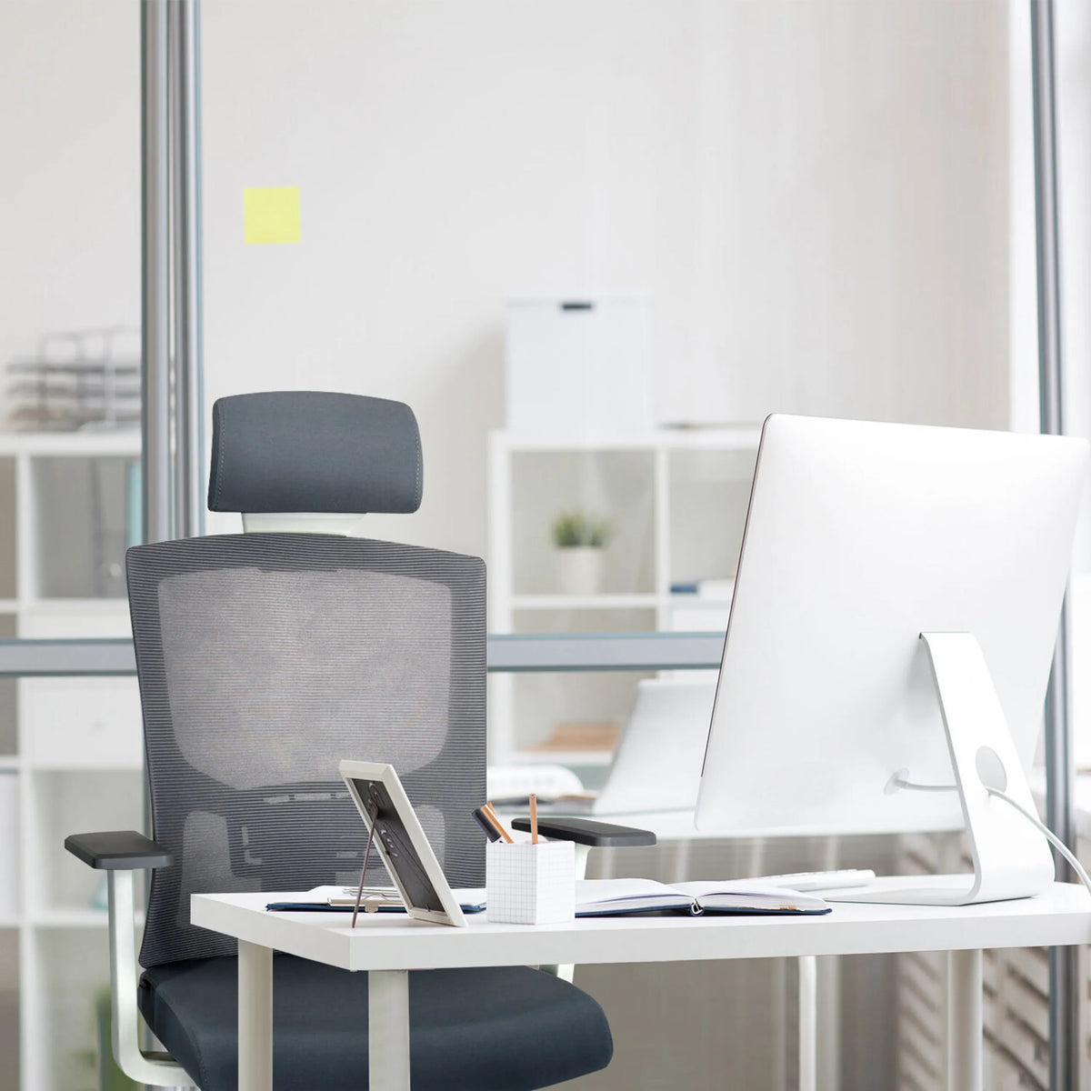 Silla de oficina profesional CAPTIVO BASE W gris con respaldo de malla y reposacabezas en un escritorio de hjh OFFICE