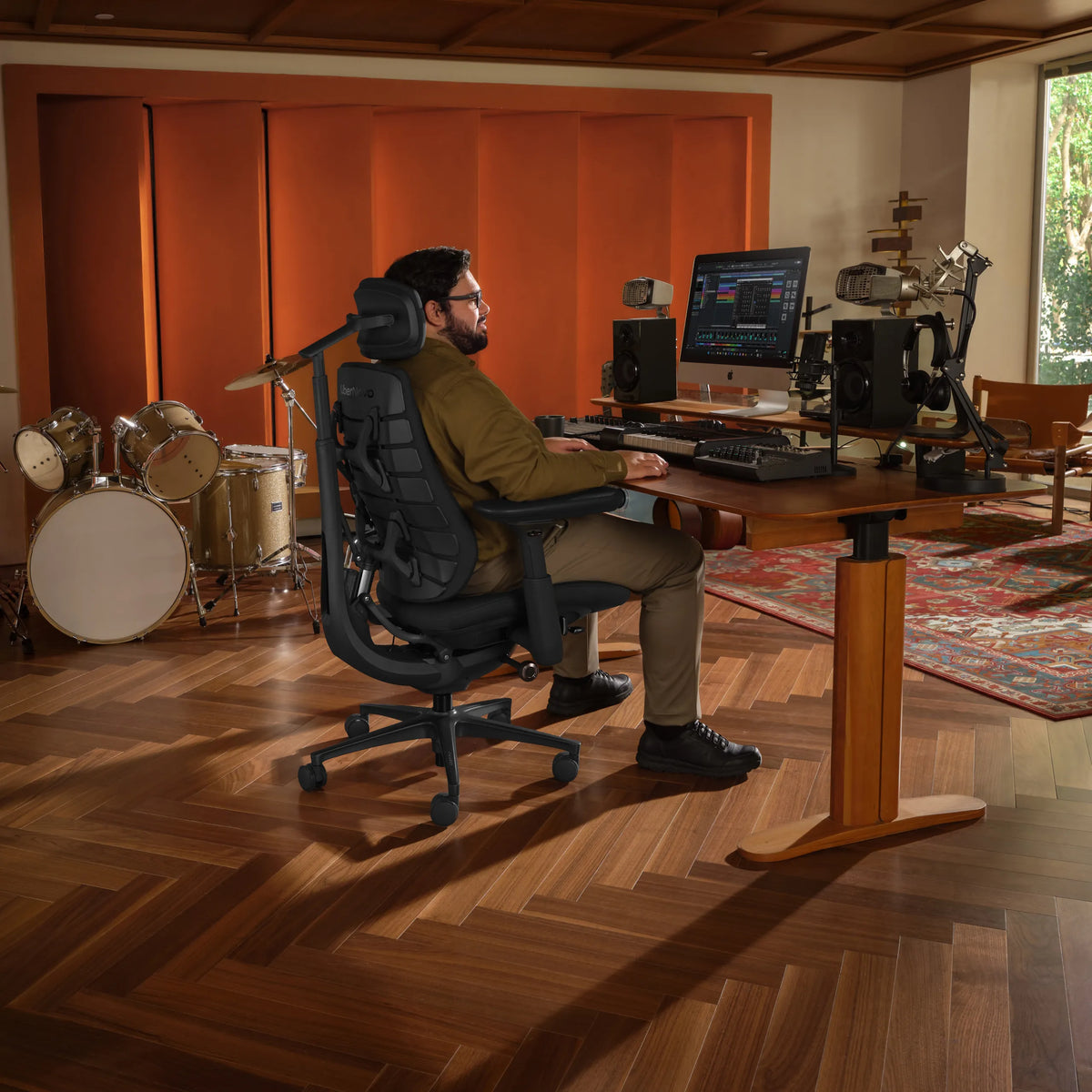 Silla de oficina LiberNovo Maxis Airflow en grafito en un escritorio regulable en altura en un estudio de música de Libernovo