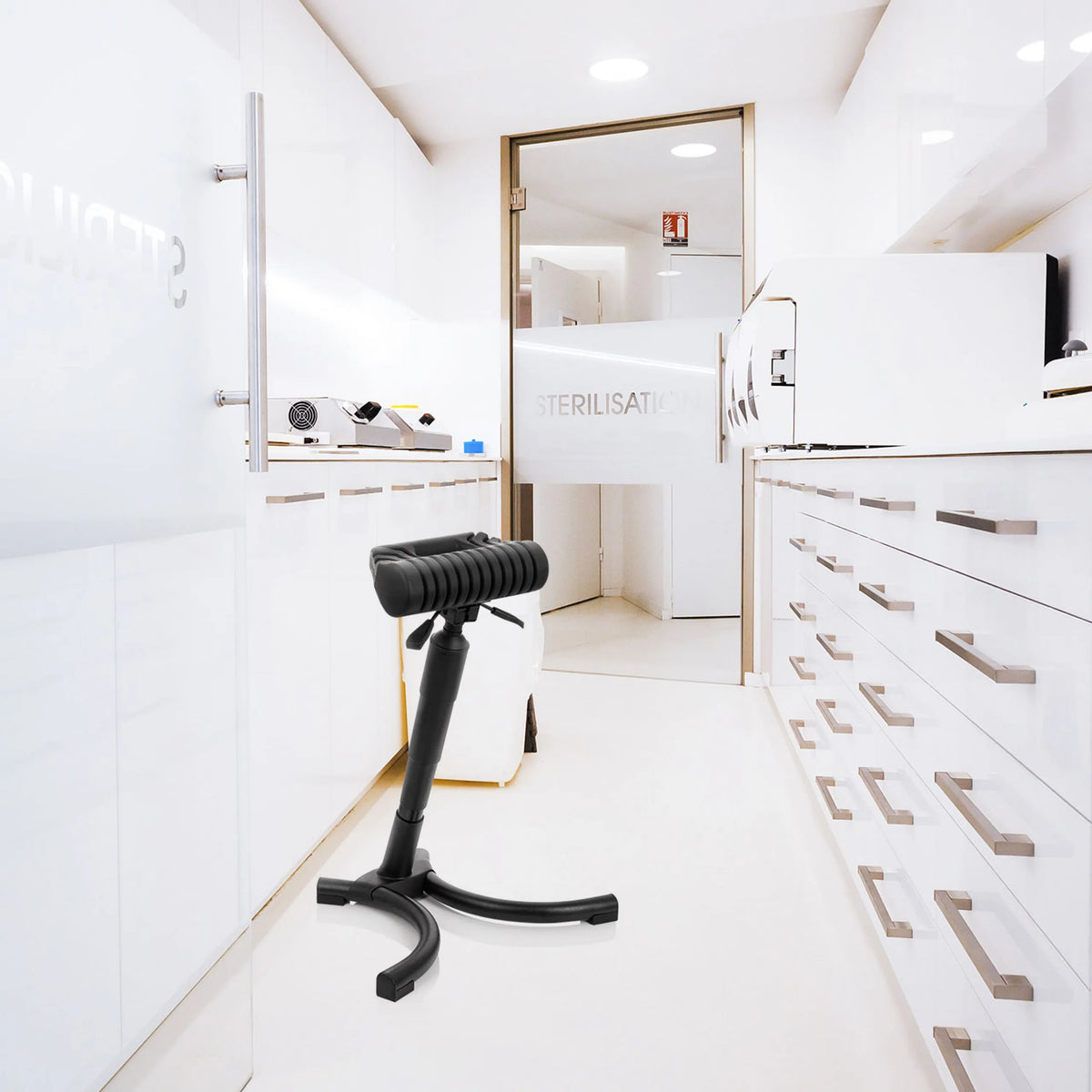 Asiento de pie TOP WORK 33 negro con asiento acolchado y base en estrella en un entorno de esterilización luminoso de hjh OFFICE