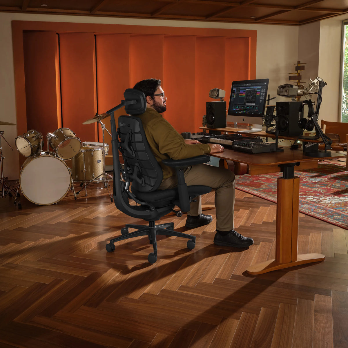 Silla de oficina LiberNovo Maxis Elektric en grafito en un estudio de música con escritorio y batería de Libernovo