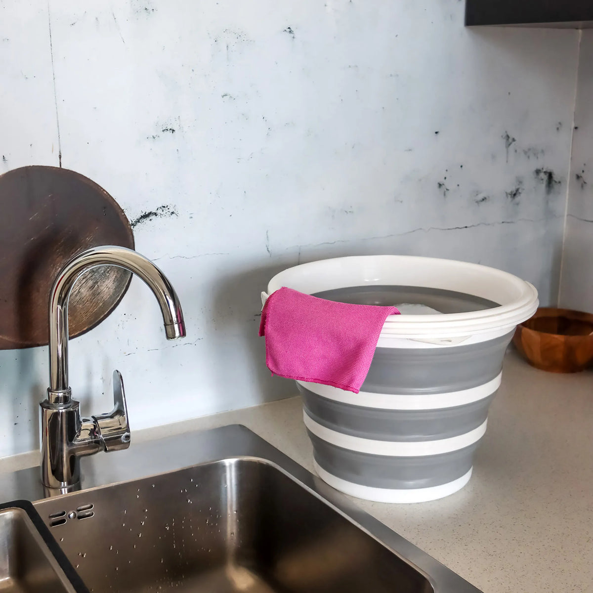 Contenedor plegable CLEAN SILR en gris y blanco con un paño rosa sobre una superficie de trabajo junto a un lavabo de hjh OFFICE