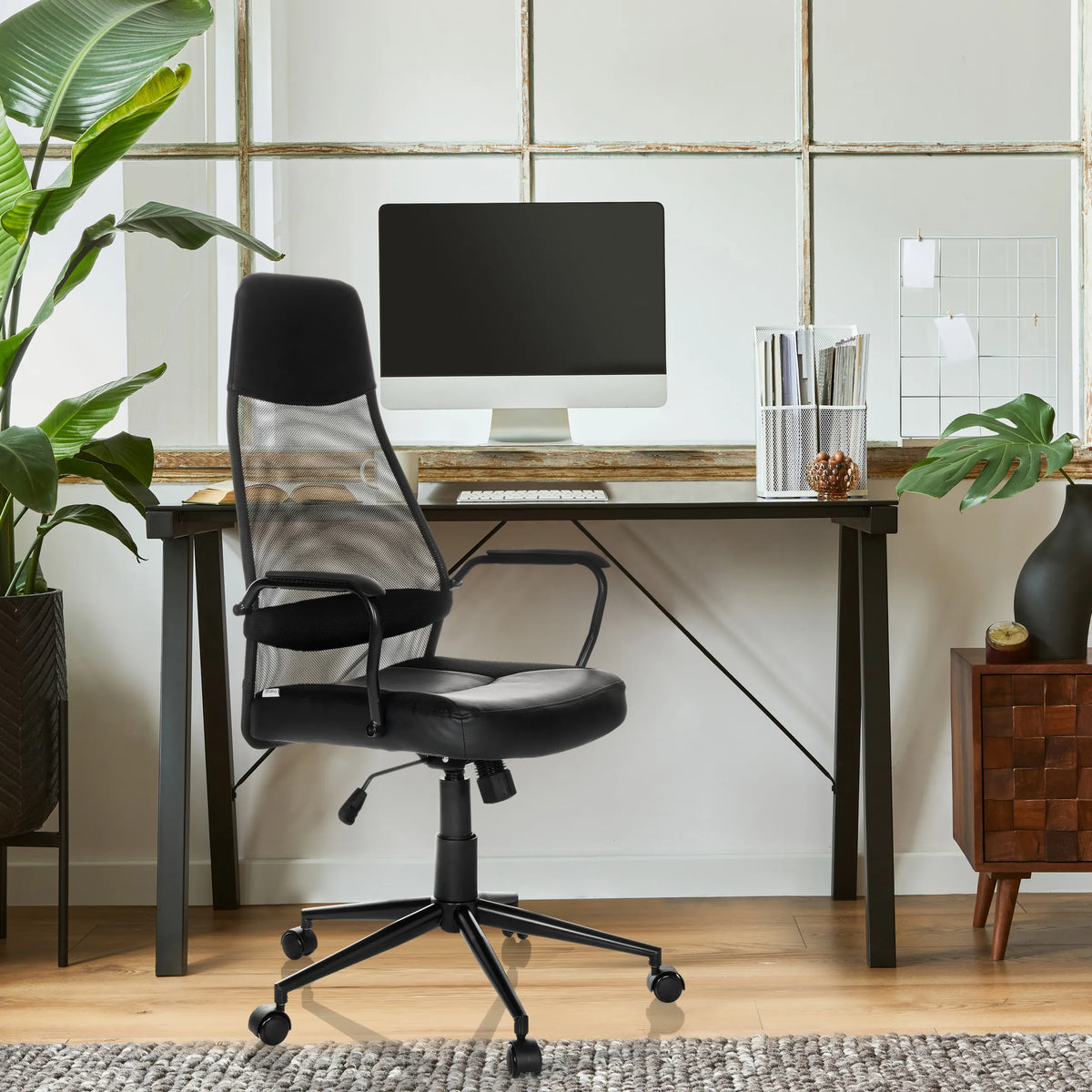 Sillón de oficina Home Office MARCOZ negro con respaldo de malla y reposabrazos frente a un escritorio de MyBuero