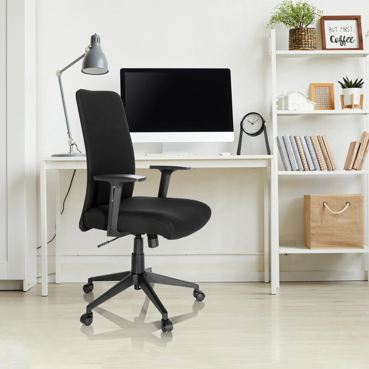 Silla Home Office COSIO I negra con reposabrazos y ruedas en un escritorio blanco de hjh OFFICE