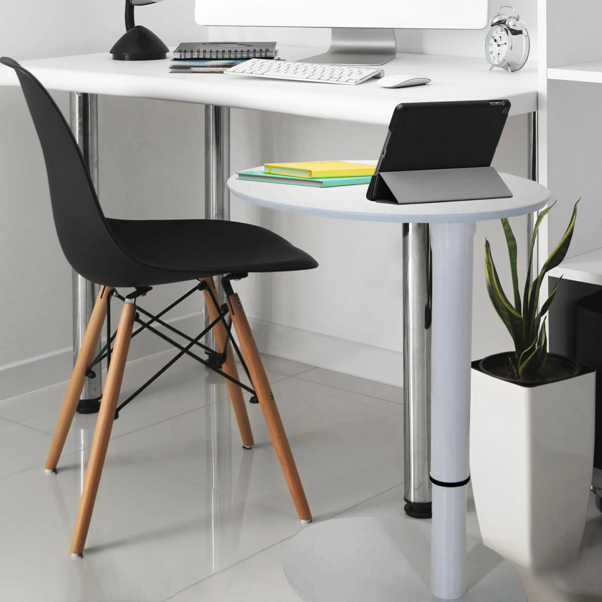 Escritorio de pie blanco STAND III con superficie de almacenamiento redonda, silla negra y una planta de interior de hjh OFFICE
