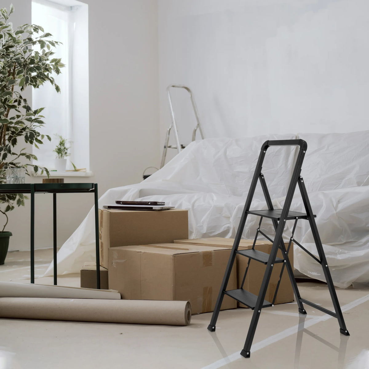 Escalera plegable SOLID W6 negra con tres peldaños en una habitación junto a cajas de mudanza de hjh OFFICE