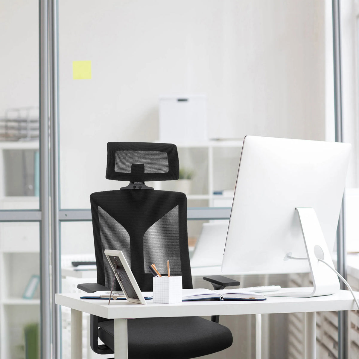 Silla de oficina profesional KODIAK negra con respaldo de malla y reposacabezas en un escritorio blanco de hjh OFFICE