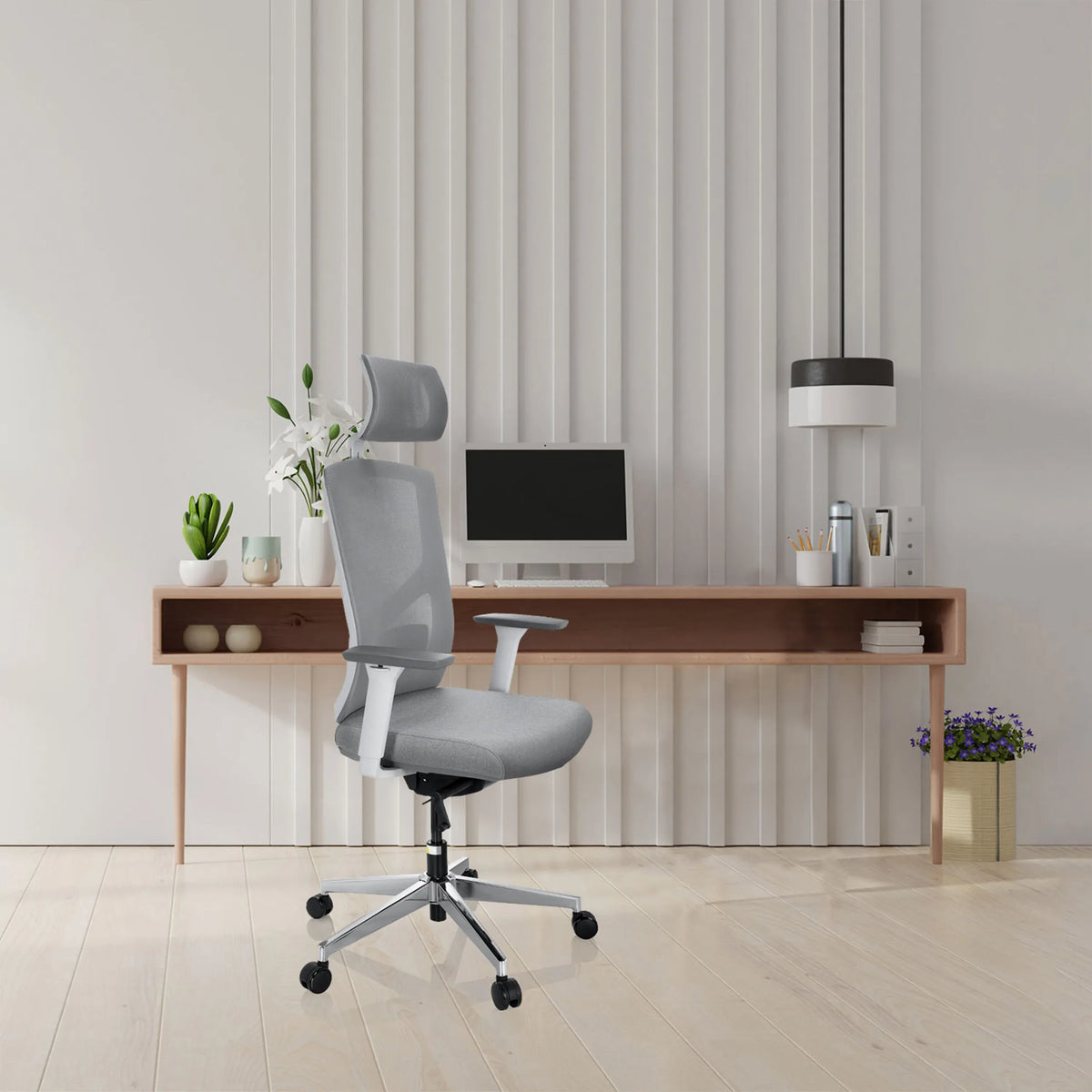 Silla de oficina profesional BRETON PRO W de color gris con reposacabezas y reposabrazos frente a un escritorio minimalista de hjh OFFICE