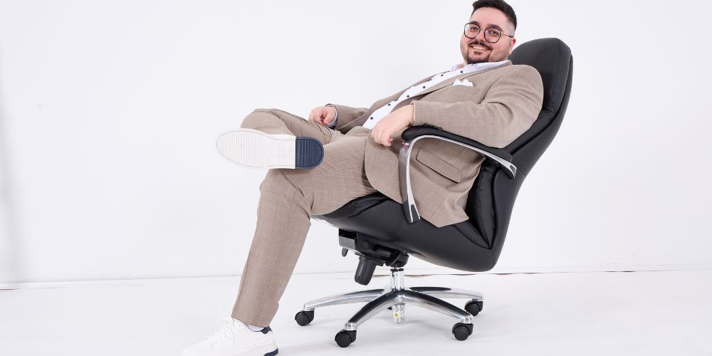 Ein Mann mit 120 kg Gewicht sitzt auf einem geeigneten Bürostuhl und lächelt