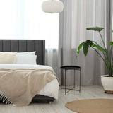 Mesa auxiliar ALLRUND de metal en color negro con tablero perforado junto a una cama de hjh LIVING