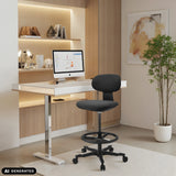 Silla de trabajo WORK MF2 negra con reposapiés y ruedas delante de un escritorio blanco de hjh OFFICE (imagen generada por IA)