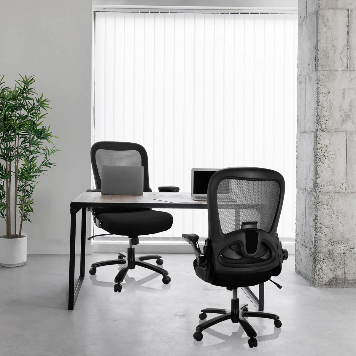 Dos sillas giratorias XXL INSTRUCTOR SW I negras con respaldo de malla en un escritorio de hjh OFFICE