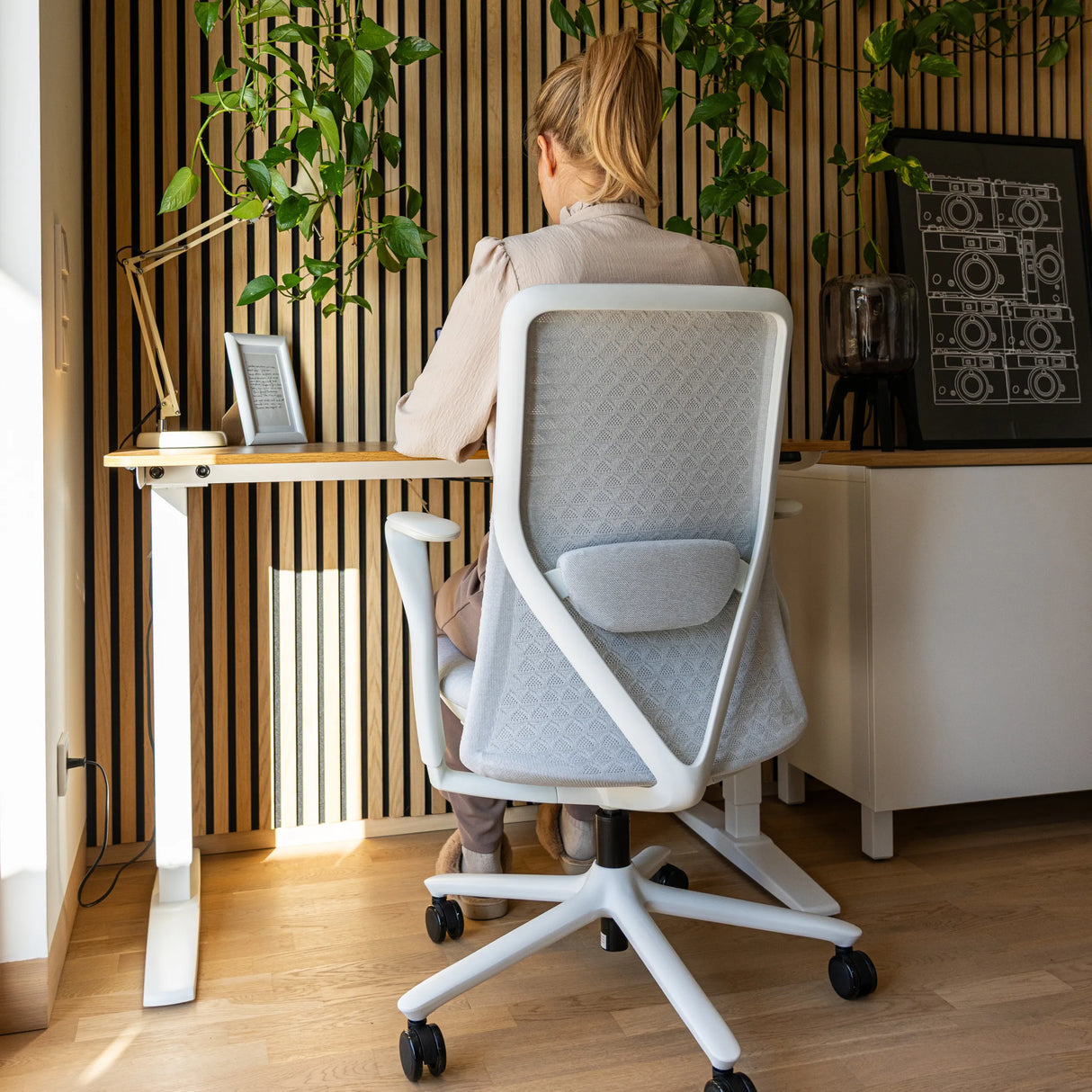 Silla alta gama VERVIO en gris claro con respaldo de malla y estructura blanca en un escritorio de hjh OFFICE