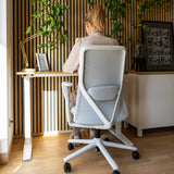 Silla alta gama VERVIO en gris claro con respaldo de malla y estructura blanca en un escritorio de hjh OFFICE