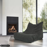Sillón de diseño Sitzolo de pana gris delante de una chimenea de hjh LIVING (imagen generada por IA)