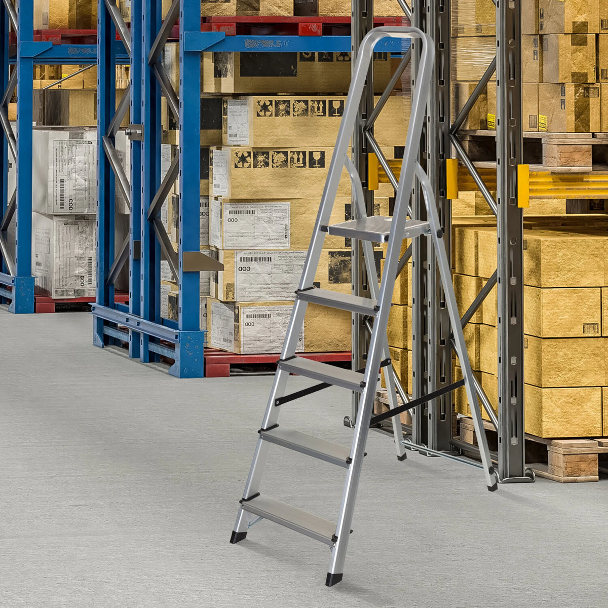 Escalera plegable de aluminio de cinco peldaños SOLID III en un almacén delante de una estantería de hjh OFFICE