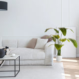 Planta artificial verde BANANE en una maceta blanca junto a un sofá de hjh OFFICE