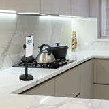 Soporte para teléfono móvil y tableta FLEXMOBI II en color negro sobre una encimera de cocina blanca de hjh OFFICE