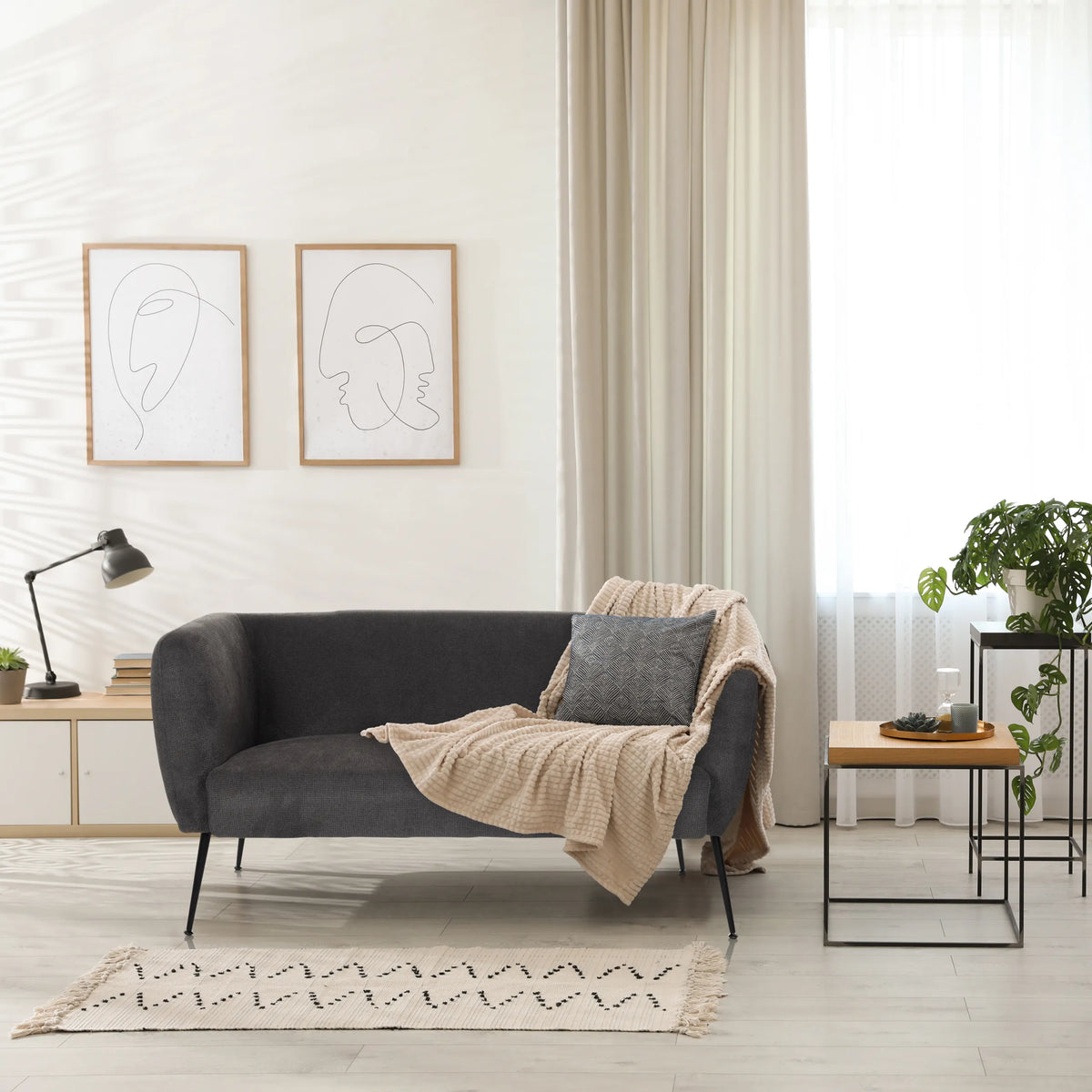 Sofá de diseño gris HAYRIVER con cojines y manta en una habitación luminosa de hjh LIVING