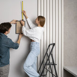 Escalera plegable SOLID W6 negra de tres peldaños en uso al colgar un cuadro de hjh OFFICE