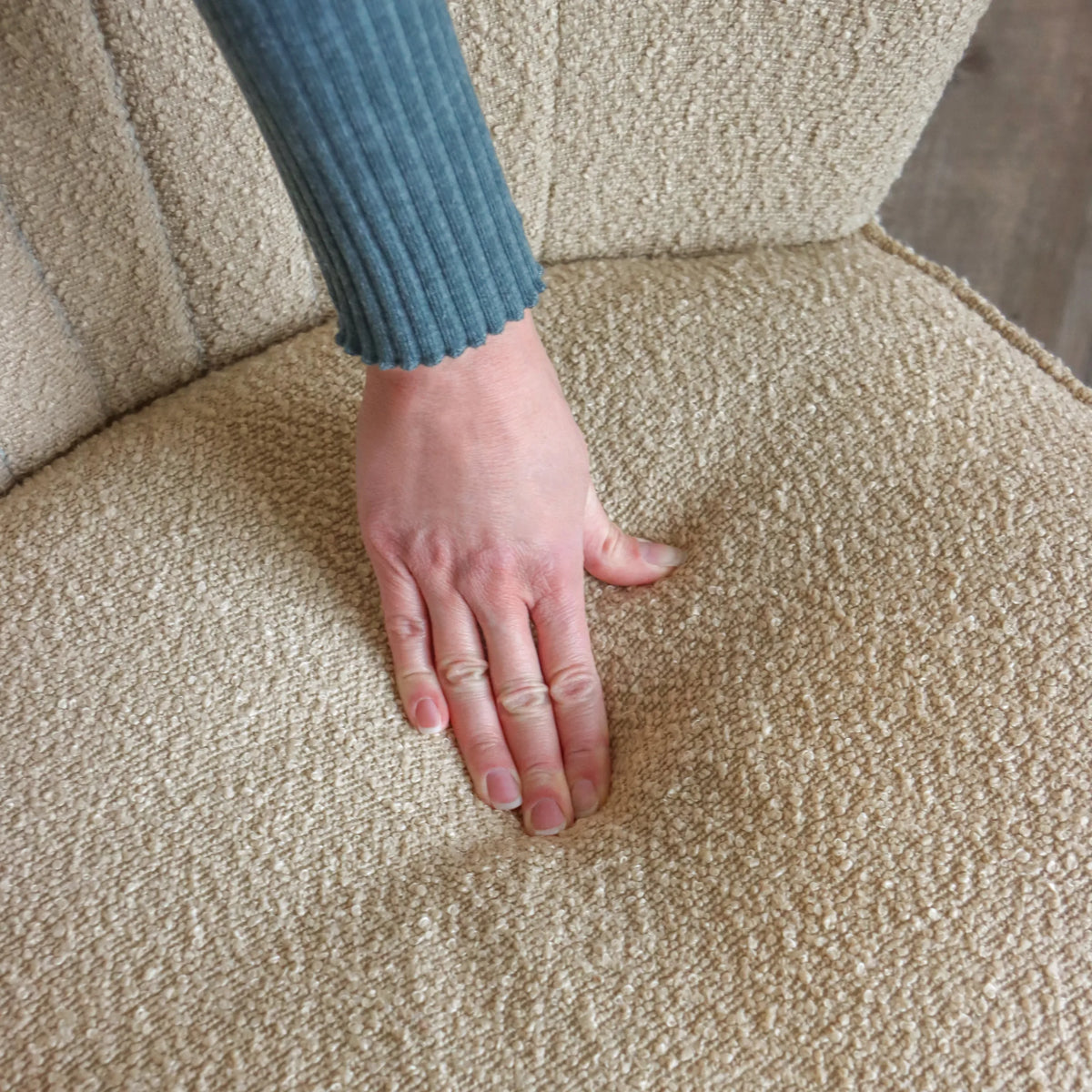 Tejido estructurado beige del sillón de diseño MANISO con una mano apoyada en el asiento de hjh LIVING