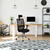 Silla de oficina profesional PROFONDO PRO negra con respaldo de malla y reposacabezas frente a un escritorio de hjh OFFICE