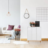 Cómoda blanca ESTHA con dos puertas y patas de madera clara en un salón luminoso de hjh LIVING