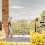 Silla de exterior blanca TUDELA XXL W en una vista exterior junto a una mesa plegable de hjh OFFICE