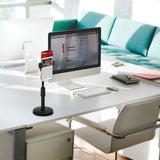 Soporte para teléfono móvil y tableta FLEXMOBI II en color negro sobre un escritorio blanco junto a un monitor de hjh OFFICE