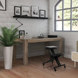 Silla ergonómica de rodillas ORTHONI negra con ruedas delante de un escritorio de madera en una habitación iluminada de hjh OFFICE