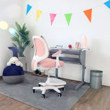 Silla para niños rosa KID ERGO con reposabrazos blancos y ruedas en un escritorio de hjh OFFICE