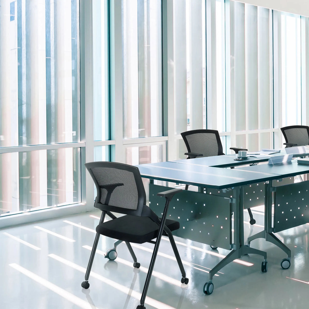 Silla plegable PRIORITY II en negro con respaldo de malla en una mesa de conferencias de hjh OFFICE