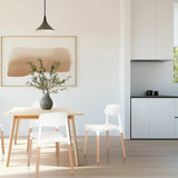 Silla de cuatro patas SCANDI E en blanco con patas de madera clara en un comedor de hjh LIVING
